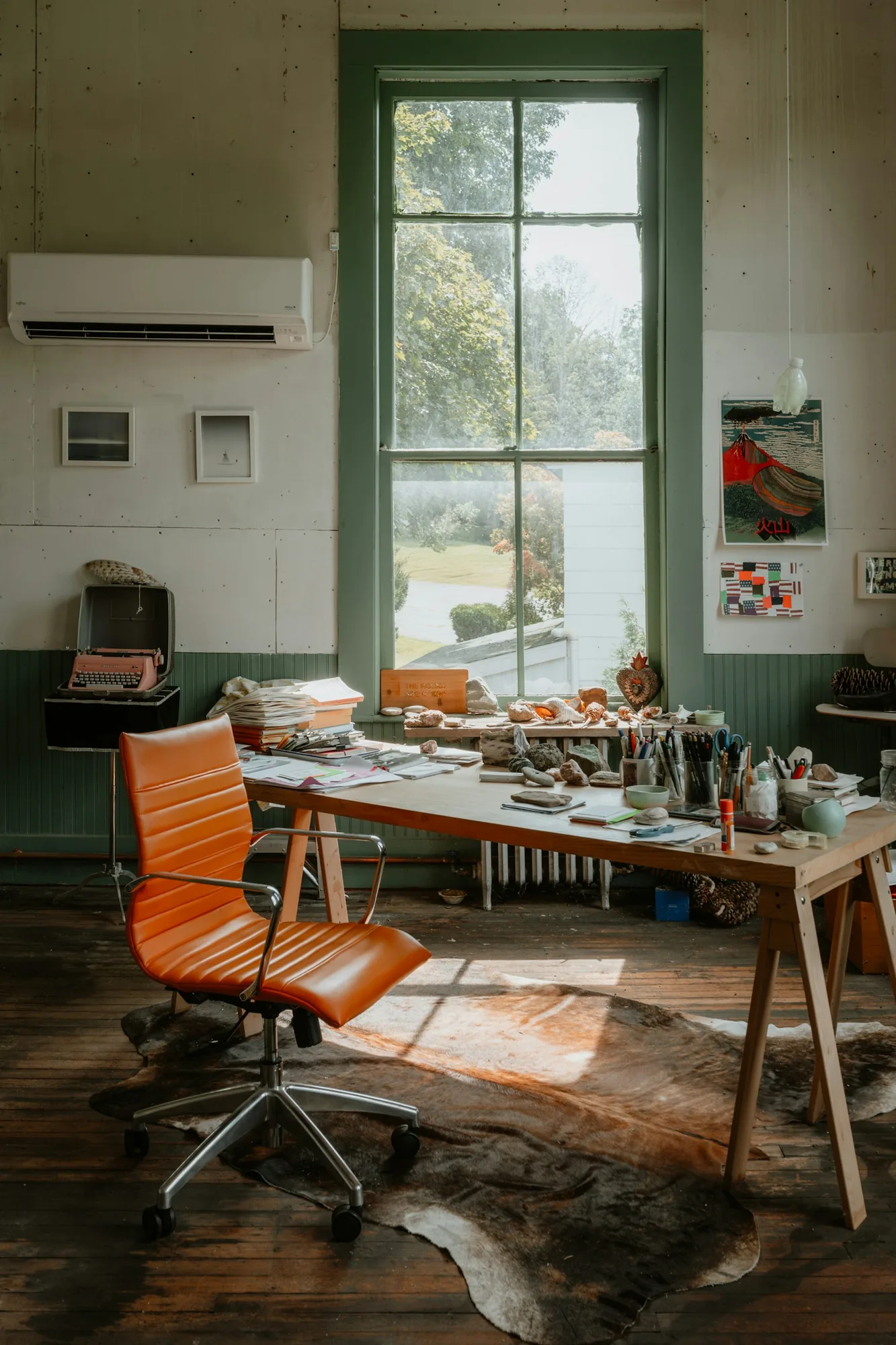 Sunlit creative studio with a work table, design materials and an orange office chair